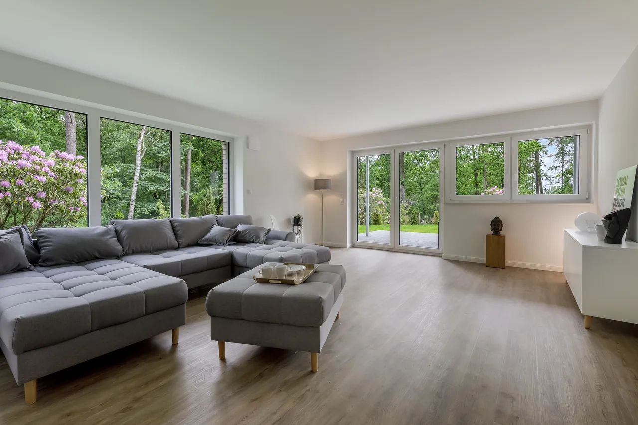 Helles Wohnzimmer mit großer Sofalandschaft und Fenstern zum Garten